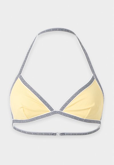Haut de bikini jaune avec bordure à motif noir et blanc et bretelle halter sur un fond blanc uni.