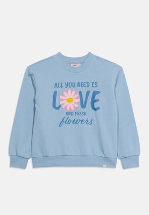 Lyseblå genser med ribbede mansjetter og kant, med teksten "Alt du trenger er kjærlighet og friske blomster" der en rosa blomst erstatter "O" i kjærlighet.