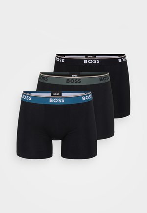 Tre slip boxer neri disposti in fila con elastici blu, verde e nero, ognuno recante il logo BOSS.