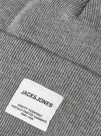 Grijze gebreide beanie met ribbeltextuur en een rechthoekig wit label met zwarte tekst waarop "JACK & JONES" en de verzorgingsinstructies staan.