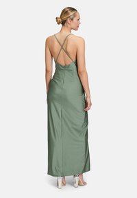 Maxikleid aus weichem, grünem Satin mit einer taillierten Silhouette. Verfügt über überkreuzte Träger und eine glatte, unverzierte Textur.