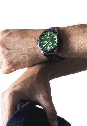 Black rubber strap watch with a green dial, silver accents, and a date display. Features a round case and bold hour markers.