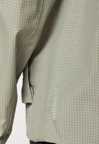 Gray waterproof jacket featuring a grid pattern, smooth texture, and a visible zip pocket with "WATERPROOF" text near the hem.