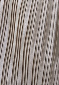 Tejido plisado en un tono beige claro con un acabado brillante, que presenta pliegues verticales espaciados uniformemente que crean un patrón texturizado.
