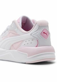 Białe sportowe buty z różowymi akcentami, z siateczkową i syntetyczną cholewką, wyściełanym kołnierzem oraz teksturowaną podeszwą. Logo umieszczone z boku.