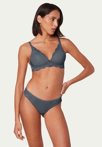 Szary komplet koronkowej bielizny, w skład którego wchodzi biustonosz w kształcie trójkąta z falbaniastymi brzegami oraz pasujące majtki typu bikini. Gładki materiał z kwiatowymi wzorami.