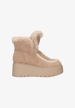 Botas de tobillo beige con ribete de piel sintética suave, parte superior de ante texturizado, forma redondeada y un detalle decorativo trenzado en la parte delantera, sobre una suela de plataforma gruesa.