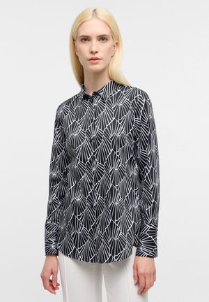 Camicia nera a maniche lunghe con motivo geometrico bianco, colletto classico e bottoni frontali. Il tessuto appare liscio e leggero.