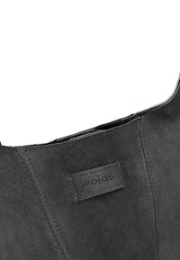 Borsa in suede grigia con una finitura testurizzata, caratterizzata da una cucitura e un'etichetta rettangolare impressa con la scritta "WOJOS."
