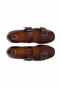 Bordeauxfarbene Lacklederschuhe mit zwei Schnallenriemen, quadratischem Zehendesign und brauner Innenauskleidung. Glatte Textur und geschlossene Form.