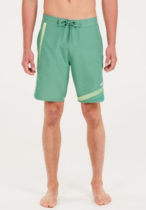 Shorts de bain verts avec taille élastique à cordon de serrage, accents en maille sur les côtés et motif à rayures en diagonale. Le tissu semble léger et à séchage rapide.