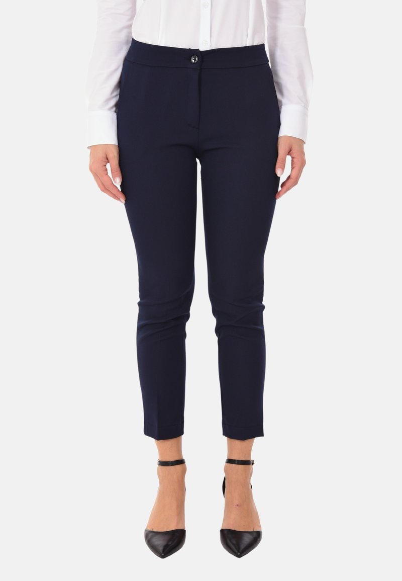Pantaloni su misura blu navy con una texture liscia, chiusura con bottone e lunghezza alla caviglia, abbinati a tacchi a punta neri.