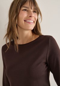 Bruine lange mouwen top met een ronde hals, gemaakt van zachte katoen. Heeft een gladde textuur en een aansluitend ontwerp zonder patronen.