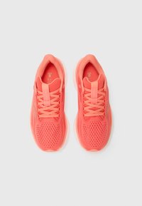 Baskets de sport corail avec une tige en mesh respirant, des superpositions texturées et des lacets plats. Semelle souple avec un design à bout rond.