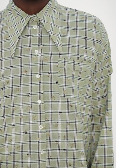 Green plaid shirt featuring white and black patterns, a patch pocket, and frayed details. Made of lightweight fabric with a classic collar.