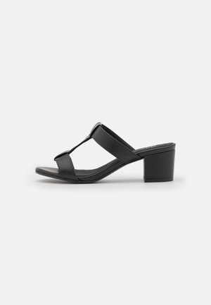 Sort åben sandal med to stropper og en lav blokhæl på hvid baggrund.