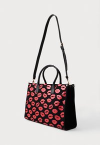 Black fabric handbag with red lip print, featuring dual black handles, a detachable shoulder strap, and a structured rectangular shape.