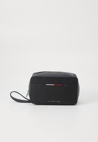 Borsa per toiletta nera con texture e chiusura con zip, caratterizzata da una striscia decorativa rossa e bianca e una tracolla staccabile. Logo visibile sul fronte.