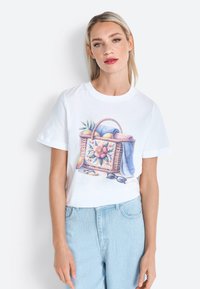 T-shirt en coton blanc avec une illustration colorée d'un panier contenant des fleurs, des fruits et des accessoires. Manches courtes et coupe décontractée.