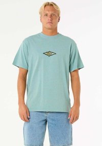 Helles blaues Baumwoll-T-Shirt mit kurzen Ärmeln, ausgestattet mit einem kleinen, rautenförmigen Logo in Gelb und Schwarz auf der Brust.