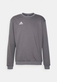 Sweat-shirt gris en tissu doux, doté d'un col rond, de manches longues et du logo Adidas blanc sur le côté gauche de la poitrine.