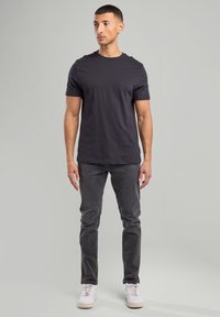 Dark gray cotton t-shirt with short sleeves, paired with dark gray denim jeans and white sneakers. Simple, fitted design without patterns.