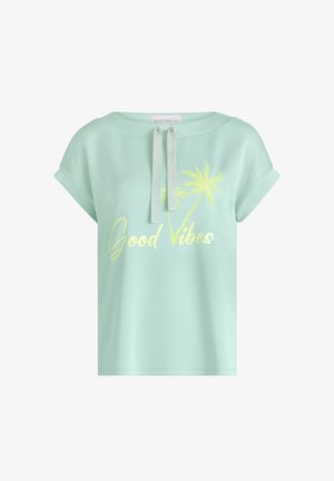 Miętowo-zielona koszulka z krótkim rękawem z podwiniętymi mankietami, srebrnymi sznurkami przy dekolcie, żółtą grafiką palmy i napisem „Good Vibes” na przodzie.