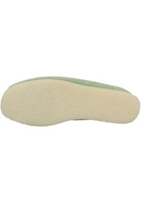 Scarpa verde in suede con una suola in gomma testurizzata di colore bianco sporco. La suola presenta un bordo liscio e arrotondato e una superficie morbida e soffice.