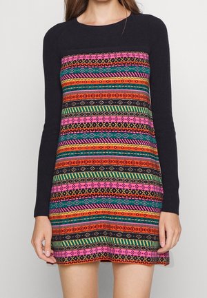 Zwarte jurk met lange mouwen met kleurrijke horizontale strepen en geometrische patronen in roze, oranje, groen, blauwgroen en geel.