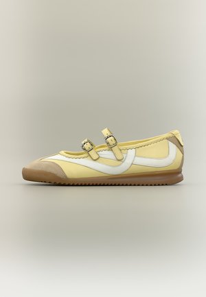 Zapato Mary Jane amarillo con dos correas de hebilla, detalle blanco Swoosh lateral, puntera beige y suela marrón acanalada.