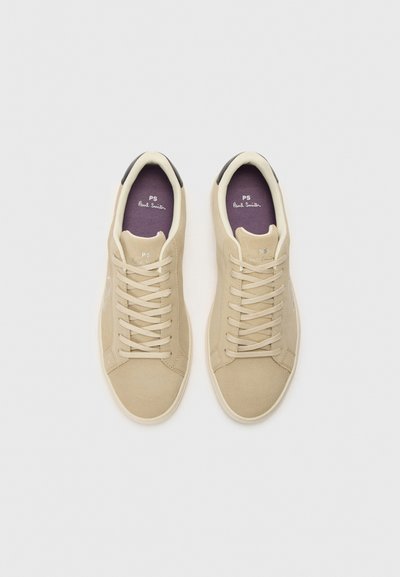 Beige mokasīni no suedes ar plakanām šņorēm, baltu gumijas zoli un melnu papēža akcentu. Violeta iekšzole ar "PS Paul Smith" zīmolu.