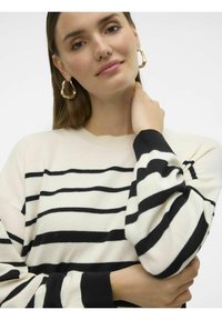 Maglione a righe in crema e nero, con scollo rotondo e maniche lunghe con polsini a costine. Texture morbida e vestibilità relaxed.