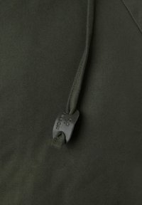 Tejido verde oliva con una textura suave; presenta un cordón con un tope de plástico negro grabado con "NOTION". Vista en primer plano.