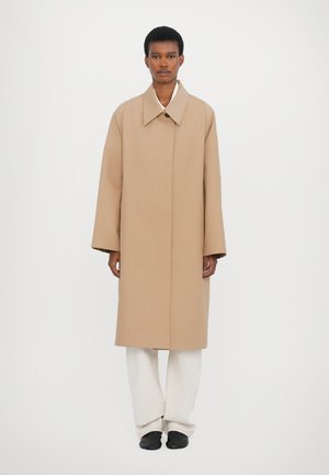 Beige, long coat with a wide collar, made of a smooth fabric. Features a single button closure and relaxed, oversized sleeves.