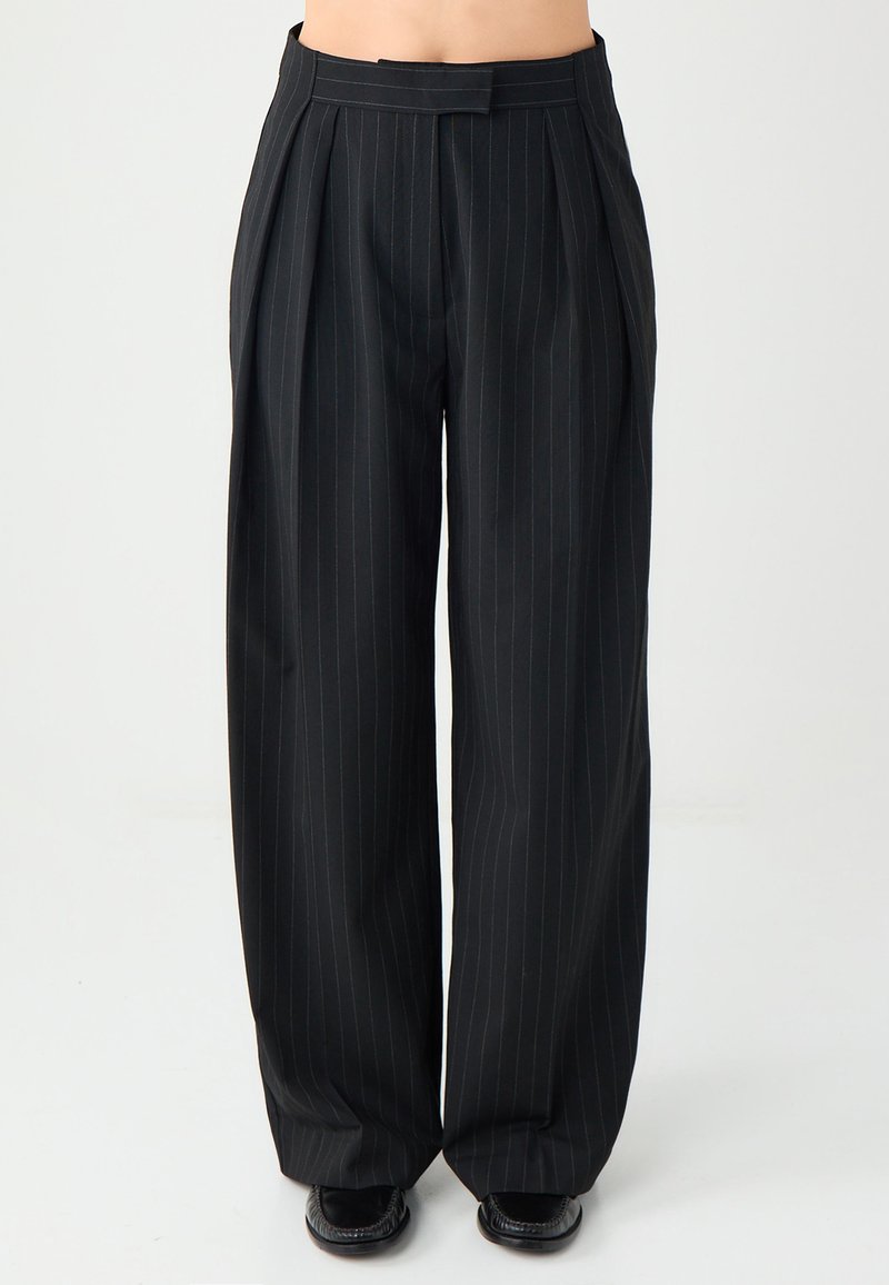 Czarne spodnie w prążki z zakładkami, wykonane z gładkiego materiału. Szerokie nogawki, z eleganckim paskiem w talii i subtelnymi niebieskimi paskami.