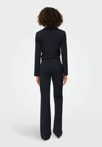 Crni odijelo s prugicama, krojeno, s dugim rukavima, slim-fit dizajnom i ravnim hlačama. Tekstuirana tkanina i precizne detalje šivanja.