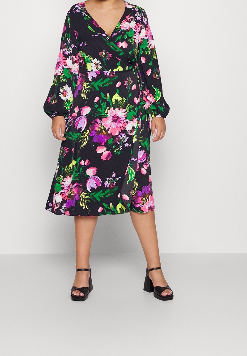 Květinové wrap šaty s dlouhými rukávy, černé pozadí, živé růžové, zelené a fialové květiny, střední délka, v kombinaci s černými sandály na blokovém podpatku.
