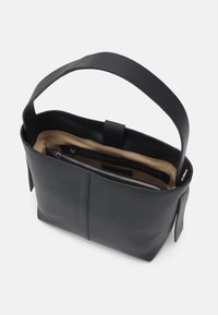 Sac en cuir noir avec une poignée large et plate. L'intérieur est doté d'une doublure beige, d'un compartiment zippé et d'un design simple et épuré.