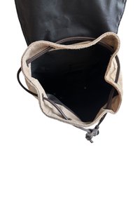 Plátěná a nylonová taška s béžovým okrajem a černým vnitřkem. Disponuje stahovací šňůrkou a viditelným šitím na okrajích.