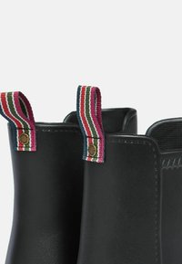 Čierne gumové členkové čižmy s pruhovanými textilnými závesmi v ružovej, zelenej a červenej farbe. Hladká textúra s zaobleným tvarom a spevnenými okrajmi.