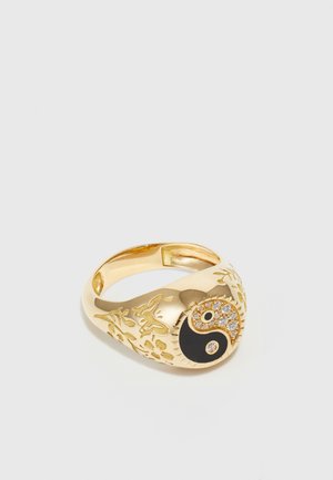 Gold ring featuring a black and white yin-yang symbol, accented with clear stones. Intricate floral patterns etched into the band.