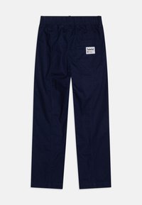 Sötétkék pamut nadrág, gumis derékkal, egyenes szabással, hátul zsebbel és Timberland logóval ellátva. Simas textúra.