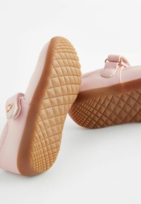 Rosa barnsandaler med en slät syntetisk ovandel, justerbar rem och en strukturerad gummisula med ett diamantmönster.