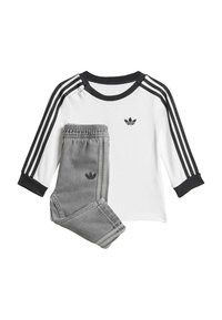 Weißes Langarmshirt mit schwarzen drei Streifen und Logo, kombiniert mit grauen Sweatpants mit Logo und passenden Seitenstreifen.