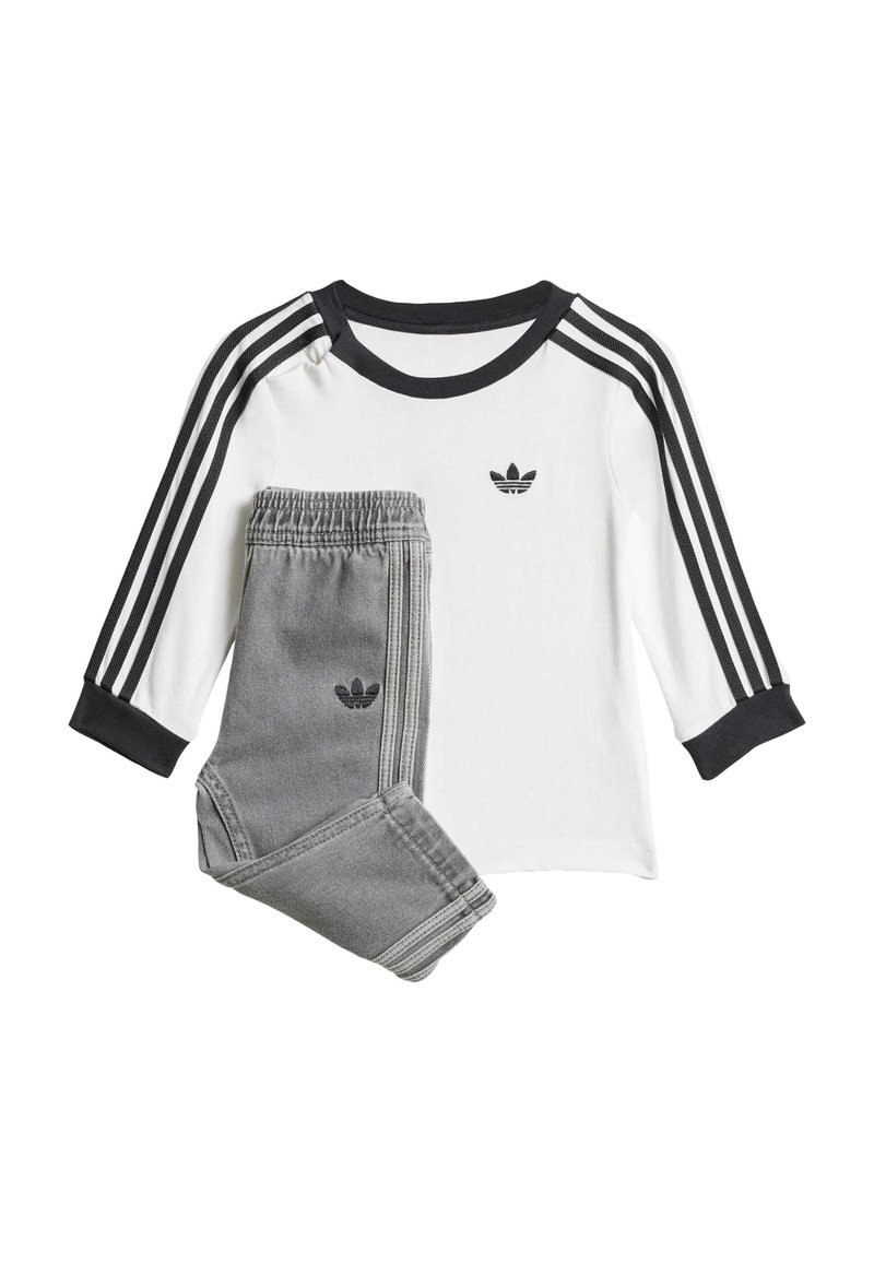 Weißes Langarmshirt mit schwarzen drei Streifen und Logo, kombiniert mit grauen Sweatpants mit Logo und passenden Seitenstreifen.