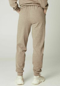 Beige joggingsbroek gemaakt van zacht, gestructureerd materiaal, met een relaxte pasvorm, elastische tailleband en zijzakken.