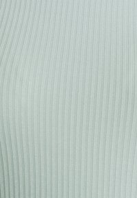 Ribbade tyger i en mjuk mintgrön färg, med ett texturerat mönster av vertikala linjer, slät yta och stretchigt material.