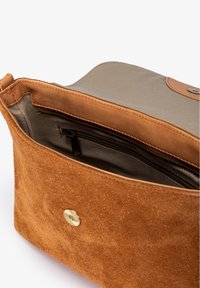 Kleine braune Wildleder- und Leinentasche mit offener Klappe, die ein Innenfach mit Reißverschluss und einer beigefarbenen Stoffauskleidung zeigt.