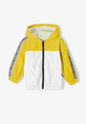 Gelbe und weiße Windjacke mit Kapuze, Frontreißverschluss, Seitentaschen und schwarzen Streifenakzenten, die Text entlang der Ärmel tragen.