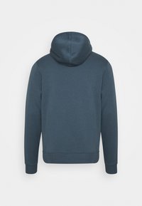 Bluza z kapturem w ciemnoniebieskim kolorze. Ma gładką fakturę, ściągacze przy rękawach i u dołu. Prosty, nieozdobiony design o dopasowanym kroju.